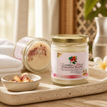 Candle jar labeled 'Paradise Island' on a wooden tray with bath bombs and flowers.