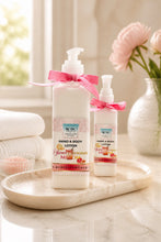 Two bottles of hand and body lotion on a marble tray with a vase of flowers in the background.