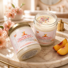 Two jars of 'Sparkling Peach' candles on a marble surface with flowers and peach slices.