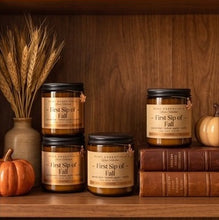 Four amber glass jars labeled 'First Sip of Fall' by High Altitude Apothecary, styled on a wooden shelf with pumpkins, books, and dried wheat.