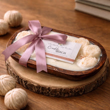 Wooden bowl with spherical candles and a pink ribbon on a wooden surface