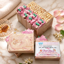 Decorative soap with floral design and a box labeled 'Pink Rose & Orange Blossom Honey' on a white background.