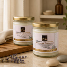 Two scented candles with gold lids on a wooden surface with lavender and stones.