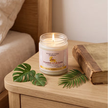 A lit candle in a clear glass jar sits on a wooden bedside table, surrounded by green leaves and a vintage book in a cozy bedroom setting.