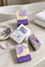 Three bars of purple and white soap on a bathroom counter with a box labeled 'Meadow Valley Soap Co'.