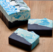Three bars of soap with blue and white swirl patterns on a wooden surface