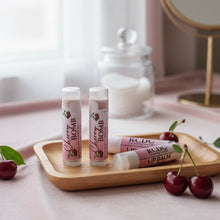 Three lip balms on a wooden tray with cherries and a mirror in the background