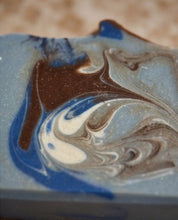 Close-up of a marbled soap bar with swirls of blue, brown, cream, and gray.