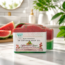 A handmade soap bar labeled 'Watermelon Sugar' by RCDC Essentials, placed on a marble countertop with watermelon slices and a bathroom background visible.