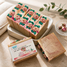 Decorative soap bars with floral designs on a white plate, surrounded by greenery.