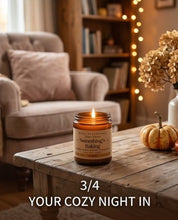 A lit candle in a glass jar sits on a rustic wooden table in a cozy living room setting, with a blurred armchair, bookshelf, string lights, and a small pumpkin in the background. Text at the bottom reads '3/4 YOUR COZY NIGHT IN'.