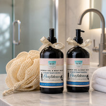 Two bottles of 'Confidence' shower gel & body wash with a loofah on a bathroom counter.