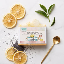A jar of Redc Essentials Lemon Poppy soap is styled on a white marble background with dried lemon slices, green leaves, black seeds, and a gold spoon.