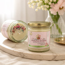 Candle jar labeled 'Basketful of Lilies' on a marble surface with a vase of flowers in the background.