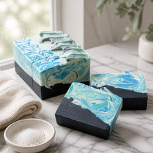 Marble-patterned soap bars on a marble surface with a towel and small bowl of salt in the background.