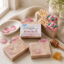 Decorative soap with floral design and a box labeled 'Pink Rose & Orange Blossom Honey' on a white background.