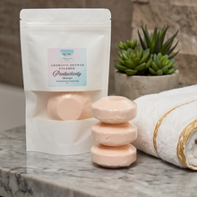 A white stand-up pouch labeled 'Aromatic Shower Bars Productivity' stands on a marble countertop beside three pale peach shower bars stacked on top of each other, with a white towel and a small potted succulent in the background.