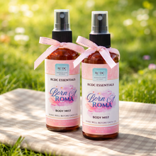 Two RCDC Essentials Born in Roma body mist bottles with ribbons on a grassy background