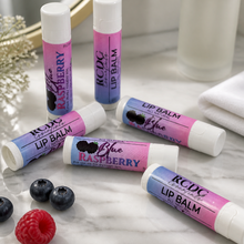Multiple lip balms with berry flavors on a marble surface.